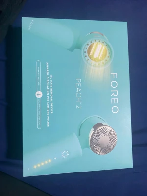 FOREO PEACH™ 2 IPL hårborttagningsenhet - FOREO PEACH™ 2 är en mintgrön IPL-hårborttagningsenhet för smidig och effektiv hårborttagning med pulserande ljus. Kommer i originalförpackning och har en modern, rund design med metallinslag. Perfekt för dig som vill ha en enkel och snabb hårborttagningsrutin.