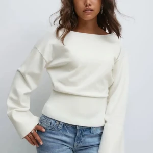 Vit långärmad topp med vida ärmar - Trendig vit topp med lång ärm och vida ärmslut. Snygg, enkel design med rund halsringning och figurnära passform. Perfekt att styla med jeans eller kjol för en clean look. Aldrig använd💕