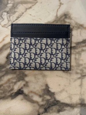  korthållare i blått och beige - . Framsidan har flera fack för kort och detaljer i skinn. Perfekt accessoar för dig som vill ha stilren och lyxig känsla i vardagen.