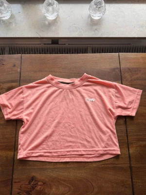 Kort aprikos t-shirt från ICANIWILL - Säljer en aprikos cropped t-shirt från ICANIWILL med rund halsringning och korta ärmar. T-shirten har en avslappnad passform och liten vit ICANIWILL-logga på bröstet. Perfekt till träning eller chill dagar.