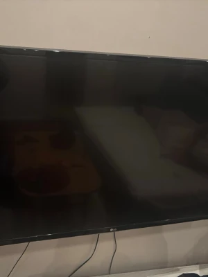 Stor svart LG platt-TV - Säljer en stor svart platt-TV från LG med tunn ram och stilren design. Perfekt för filmkvällar eller gaming. TV:n har väggfäste och flera anslutningsmöjligheter. Passar snyggt i vardagsrummet och ger en modern känsla.