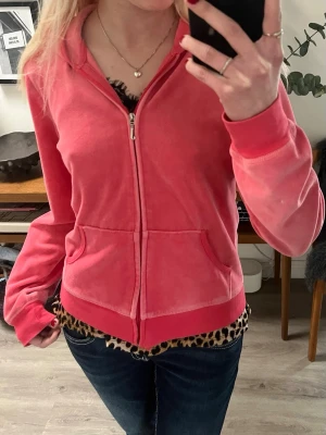 Juicy Couture rosa velour hoodie - Juicy Couture hoodie i mjuk rosa velour med dragkedja framtill och fickor. Ikoniskt guldfärgat emblem med strassdetaljer på ryggen och huva. Perfekt för en chill och trendig look. L men passar mig som har XS/S!! 
