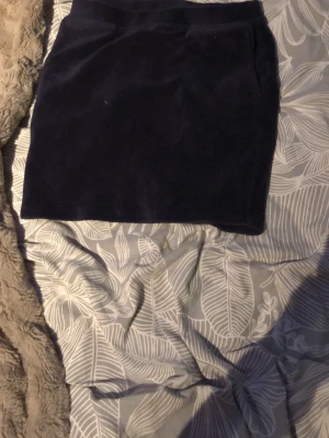 Mörkblå manchesterkjol - Snygg mörkblå kortkjol i manchester med enkel design och rak passform. Kjolen har en mjuk struktur och passar perfekt till en avslappnad stil. Inga synliga detaljer som knappar eller dragkedja på framsidan.