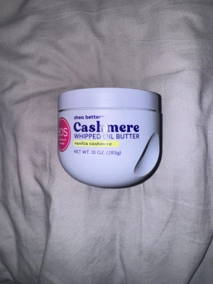 EOS Cashmere Whipped Oil Butter - Lyxig body butter från EOS i doften Vanilla Cashmere. Kommer i en vit rund plastburk med lila och gula detaljer. Innehåller sheasmör och oljor för extra återfuktning och mjuk hud. Perfekt för dig som vill ha en krämig och väldoftande hudvård.