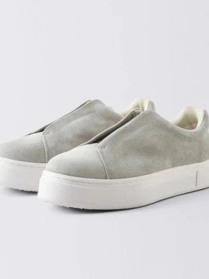 Eytys skor - Stilrena slip-on sneakers i ljusgrå mocka med vit platt sula och lila detalj på hälen. Skorna har minimalistisk design utan snörning och en mjuk, rundad tå. Perfekta för en clean och modern look.
