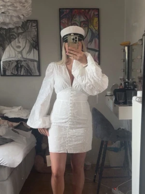 Adoore klänning  - Säljer nu min vita studentklänning från adoore med djup v-ringning och stora puffärmar. Klänningen har knappar framtill och markerad midja. Knappen längst ner har ramlat av men tycker att man inte tänker på de! Perfekt till student eller sommarens festligheter. 