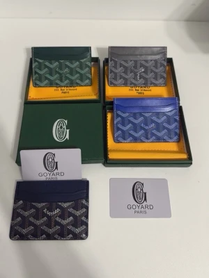 Card holder - (Du får bara välja en)Snygga korthållare från  i klassiskt mönster. Finns i grönt, grått, blått och marinblått med vit logga och detaljer. Tillverkade i exklusivt skinn med ikoniska grafiska tryck. Perfekt för dig som vill ha en stilren och lyxig accessoar.