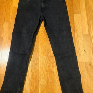 Svarta jeans W30 L30 - Svarta med skinny fit och klassisk femficksdesign. Jeansen har normal midja och raka ben som smalnar av. Tillverkade i ett stretchigt jeansmaterial som sitter tajt och bekvämt. Perfekta för dig som gillar en stilren och enkel look.