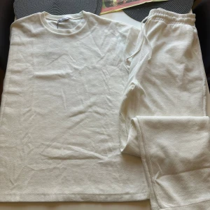 Vit ribbad t-shirt från Zara och byxor i XL - Vit ribbad t-shirt och byxor från Zara i storlek XL. T-shirten har rund halsringning och är tillverkad i ett mjukt, strukturerat material som känns skönt mot huden. Enkel och clean design som passar perfekt till ett avslappnat set. Ett myssett