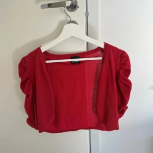 Röd glittrig bolero - En röd glittrig bolero i strl S (passar som M oxå). Mycket bra skick!