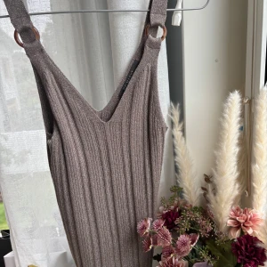 Glittrig guld linne med knappar  - Supersnygg glittrig ribbad festlinne i guld, med breda axelband och coola ringdetaljer i plast. V-ringad framtill och figurnära passform. Perfekt på fest. Det är en xs men passar s! Ny utan prislapp, aldrig använt 