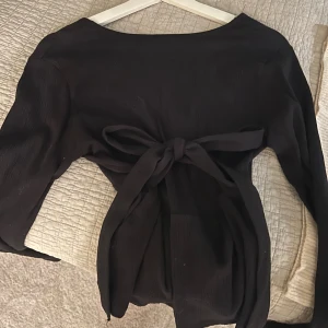 Svart topp med rosett  - Säljer denna super gulliga urringade topp med en söt rosett som du knyter i ryggen❣️Tveka inte på att höra av er vid frågor eller funderingar!