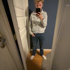 Grå hoodie från Lexington med dragkedja - Säljer en ljusgrå hoodie från Lexington i storlek 146/152. Tröjan har huva, dragkedja framtill och är tillverkad i mjuk bomullsmix. Perfekt för en chill och avslappnad stil. Klassisk Lexington-logga på bröstet och ribbade muddar vid ärmslut och nederkant.