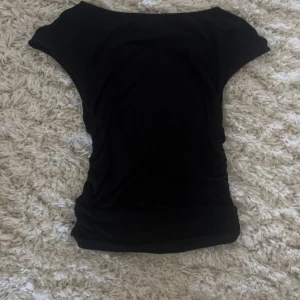 Svart topp - Figurnära Svart topp med scrunvh i sidorna använd fåtal gånger