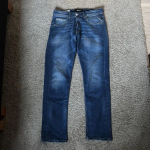 Replay Grover jeans straight fit blå - Säljer ett par Replay Grover jeans i klassisk blå tvätt med straight fit. Jeansen har fem fickor, snygga slitningar och detaljerade bakfickor. Tillverkade i jeansmaterial med normal passform och raka ben. Perfekta för dig som gillar en tidlös look.