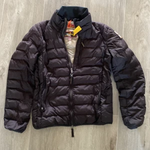 Svart dunjacka från Parajumpers S - Säljer en svart dunjacka från Parajumpers i storlek S. Jackan är superlätt, har quiltad design, dragkedja framtill och klassisk gul detalj vid kragen. Broderad logga på ärmen och två sidofickor med dragkedja. Perfekt för kalla dagar. Det ändå dåliga är fickorna där det saknas kragen så dem går inte att stänga, men de går att lösa hos en skräddare