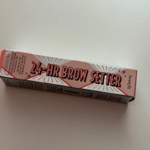 Benefit 24-HR Brow Setter gel - Benefit 24-HR Brow Setter är en transparent ögonbrynsgel som formar och fixerar brynen i upp till 24 timmar. Kommer i en snygg silvrig tub med rosa och svart text. Perfekt för att hålla brynen på plats hela dagen utan att kännas stel. Nypris 379 kr