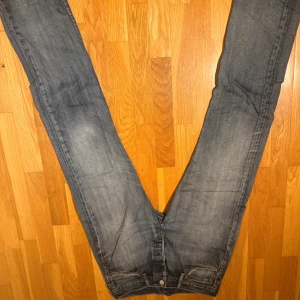 Levi's 501 jeans W32 L34 blå - Klassiska Levi's 501 jeans i blå tvätt med raka ben och normal passform. Jeansen har fem fickor, knappgylf och tydliga slitningar för en cool, avslappnad look. Tillverkade i bomull och har den ikoniska läderpatchen bak i midjan.