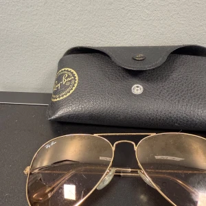 Ray-Ban aviator solglasögon guld - Snygga Ray-Ban aviator solglasögon med klassisk guldig metallbåge och bruna tonade glas. Kommer med original svart fodral med Ray-Ban-logga. 