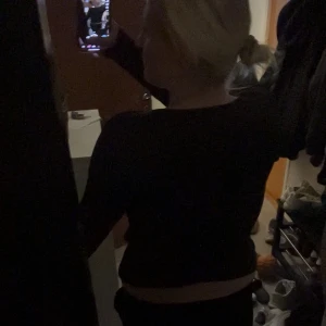 Svart långärmad croppad topp med cutouts - Säljer en svart långärmad croppad topp med coola cutouts och twistad detalj framtill. Toppen har en tajt passform och är perfekt för dig som vill sticka ut med en edgy look. Materialet känns mjukt och stretchigt mot kroppen.