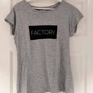 Grå t-shirt med tryck - Grå T-shirt från Lager 157 med tryck ”factory.” på i storlek M. I mycket gott skick och använd fåtal gånger💕