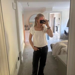 Vit blus med puffärm och fyrkantig ringning - Säljer en söt vit blus med korta puffärmar och fyrkantig ringning. Toppen har en avslappnad passform och smockdetalj upptill. Perfekt till jeans eller kjol beroende på vad som passar dig. Materialet känns mjukt och är väldigt skönt!