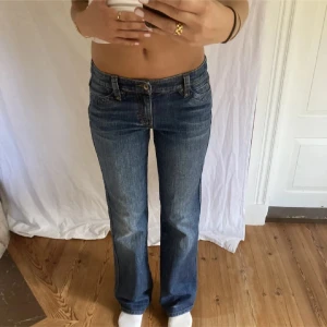 Blå bootcut jeans med låg midja - Snygga blå jeans med bootcut passform och låg midja. Klassisk femficksmodell med detaljerade bakfickor och knappstängning fram. Midjemått: 39 cm (rätt över). Innerbenslängd: 80 cm. Jag är 170 cm på bilderna! Inga defekter☺️