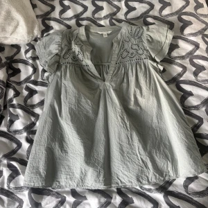 Ljusgrön blus med broderade detaljer - Supersöt ljusgrön blus från H&M med broderade detaljer och hålmönster upptill. Blusen har korta, volangiga ärmar och en v-ringad halsringning. Tillverkad i mjuk bomull, perfekt för vår och sommar. Knappt använd då jag inte gillar dessa typer av tröjor. Köp i somras för 250kr, säljer för halva priset🥰