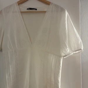 Vit klänning från Zara - Superfin vit klänning från Zara med v-ringning och korta puffärmar. Klänningen har broderade detaljer och spetsinslag och passar perfekt till student eller midsommar. Aldrig använd, superfint skick. Slutsåld på hemsidan☺️