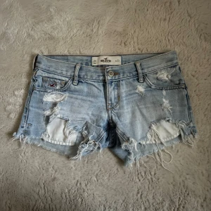 Ljusa slitna jeansshorts Hollister lågmidjade  - Säljer ett par ljusblå jeansshorts från Hollister med slitningar!  Midjemått rakt över:36cm! 