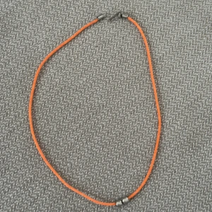 Orange halsband med metallpärlor - Ett enkelt och stilrent halsband med en tunn orange snodd och två små silverfärgade metallpärlor. Perfekt för dig som gillar minimalistiska accessoarer med en färgklick. Det är 45cm långt 🧡
