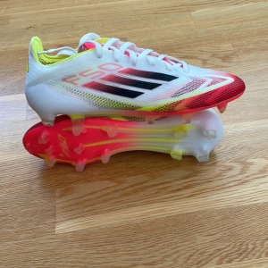 Adidas F50 Elite - Säljer ett par Adidas F50 elite fotbollsskor med snygg design i vitt, rött och gult. Aldrig använda men de har lite smuts fläckar. Påse tillkommer inte, och det är inte originella skosnören.  Nypris runt 3200.