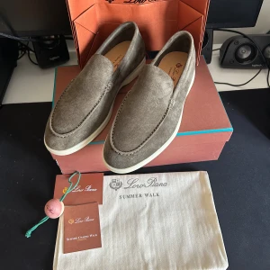 Loro Piana Summer Walk mockaloafers - Snygga loafers från Loro Piana i modellen Summer Walk. Skorna är i mjuk brun mocka med vit sula och har en klassisk, stilren design. Perfekta för en clean och avslappnad look. Kommer med originalpåse och box.