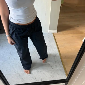 Marinblå byxor med snörning - Säljer ett par marinblå byxor med loose passform och elastisk midja med snörning. Byxorna har breda ben och är gjorda i ett lätt syntetmaterial som passar perfekt🥰