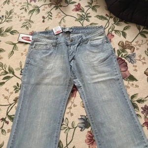 ljusblå bootcut jeans Star Lifers - Ljusblå jeans från star lifers med bootcut passform. Jeansen är ultra low waist och nya med lappen kvar. Det är vintage från 2000-talet och aldrig använda. Tillverkade i 100% bomull. Storleken är 31x32, tänk på att midjestorleken kan vara större än din vanliga eftersom dem är så lågmidjade. Jag brukar ha 27 eller 28 vanligtvis