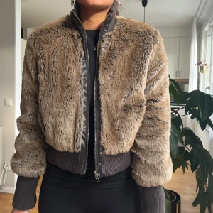 Brun pälsjacka med ribbade muddar - Säljer en snygg pälsjacka i brunt med dragkedja framtill och breda ribbade muddar vid ärmar och midja. Vintage. 