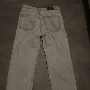 Gråa Gina Tricot straight jeans - Säljer ett par Gina Tricot jeans i grå denim. Byxorna har raka ben, fem fickor och normal passform.