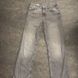 Grå raka jeans från Zara - Snygga grå jeans från Zara i rak modell med klassisk femficksdesign. Jeansen har en medel midja och är tillverkade i mjukt denimtyg. Perfekta för dig som gillar en stilren och avslappnad look.