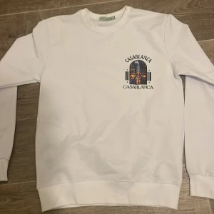 Vit sweatshirt från Casablanca S - Säljer en vit sweatshirt från Casablanca med tryck av en stadssilhuett och logga både fram och bak. Tröjan har rund hals, långa ärmar och är i mjukt material. Perfekt för dig som gillar streetstyle och vill sticka ut med snygg grafik.