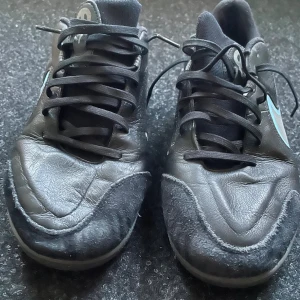 Nike Tiempo svart/blå futsalskor - Säljer ett par Nike Tiempo fotbollsskor i svart med ljusblå detaljer och logga. Använda en säsong priset kan diskuteras . Skorna har snörning, rund tå och platt sula med greppigt mönster. Ovandelen är i skinn och syntet, med förstärkta partier framtill. Perfekta för inomhusspel eller futsal. 