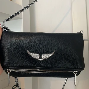 Zadig & Voltaire väska  - Snygg svart Zadig&Voltaire axelväska i skinn med kedjerem och silverfärgad dragkedja. 