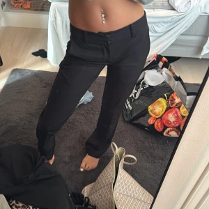 Svarta kostymbyxor med raka ben - Snygga svarta lågmidjade kostymbyxor med raka ben och klassisk passform. Byxorna har hällor för bälte, diskreta fickor och stängs med dragkedja och knapp. Perfekta för en clean och stilren look. Materialet känns mjukt och följsamt.  ALDRIG ANVÄNDA