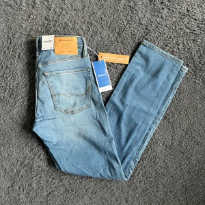 Jack & Jones Slim Glenn ljusblå jeans - Säljer ett par helt nya ljusblå Slim Glenn jeans från Jack & Jones. Jeansen har klassisk femficksdesign, raka ben och snygga kontrastsömmar. OBS har tappat en ovänstlig knapp som syns på sista bilden. Midja 34cm längd 99cm. Ifall det inte finns någon bild i annonsen där jag bär plaggen jag säljer så är det för att jag ej kan ha storleken heller passformen, så kolla måtten för storlek och googla på modellnamnet för passform 😉
