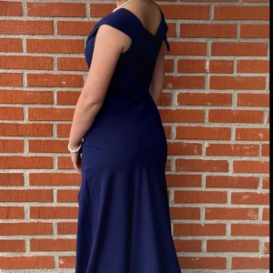 Marinblå långklänning med slits - Använd en gång (bal)!                                     Elegant marinblå långklänning med offshoulder-skärning och figurnära passform. Klänningen har en snygg slits framtill och vackra draperade detaljer över bysten. Perfekt för bal eller festliga tillfällen. Materialet känns mjukt och följsamt.