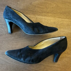 Svarta mocka klackskor från Rizzo - Klassiska svarta pumps från Rizzo i mocka med spetsig tå och smal klack. Snygg och tidlös modell som passar till många olika outfits. Insidan är ljus och mjuk för extra komfort. Perfekta för dig som gillar stilrena och eleganta skor.