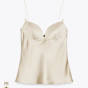 Champagnefärgad satinlinnetopp från Zara - Supersnygg champagnefärgad linne-topp från Zara i glansig satin med tunna axelband och formade kupor. Toppen är helt ny men beställde en storlek för stor - inga defekter med den utan säljer billigare här pågrund av storleken💞😇den sitter som en M men banden är lite längre än jag önskat