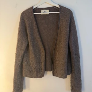 Day Birger et Mikkelsen kofta - Brun/grå kofta från DAY Birger et Mikkelsen Woman. Koftan har en öppen design utan knäppning och är dekorerad med pärlbroderier längs nederkanten och ärmarna. Storlek M. Fint skick men lite nopprig, se bild 2. Och har tyvärr en litet hål, se sista bild. Men det är väldigt litet. Nypris runt 2000kr