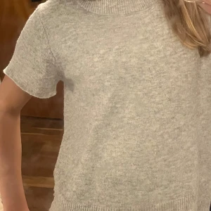Grå stickad polotröja med kort ärm - Mysig grå stickad polotröja med korta ärmar och ribbad krage. Perfekt för lager-på-lager och chill dagar. Enkel och stilren design som passar till det mesta. Pris går att diskuteras. Passar S och xs 