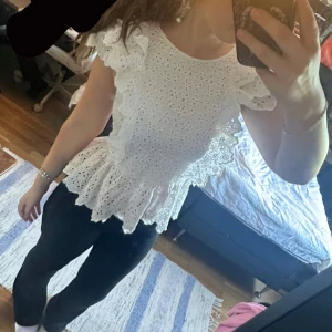 Vit blus med volang  -  vit blus med broderade blommor och volangdetaljer vid axlar och nederkant. 💕