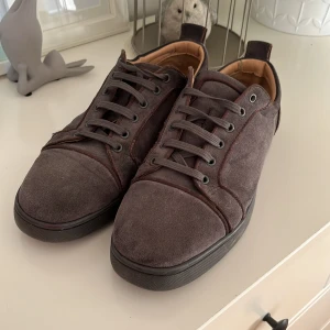 Mörkbruna mockasneakers med röd sula - Bruna mocka skor med röd sula. Dust bag tillkommer